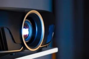 Close-up of a black projector lens with the words "ZOOM LENS OPTICAL" written on it.